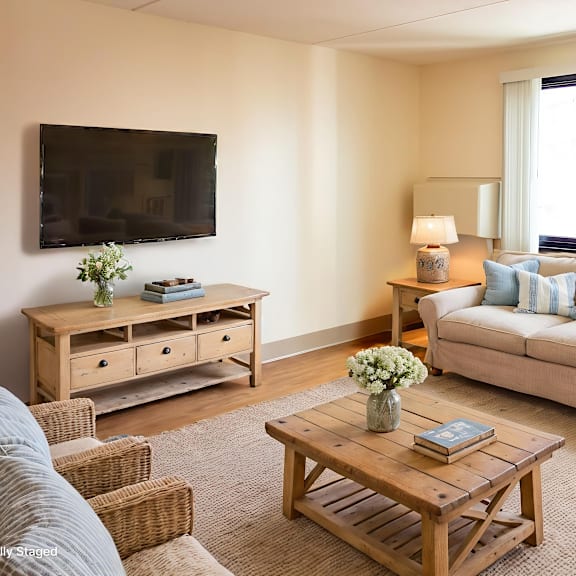 a living room with a couch, a coffee table, and a television mounted on the wall.