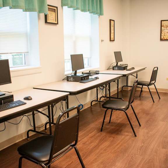 a row of desks with computers and chairs in a room