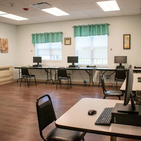 a computer room with desks and chairs and a keyboard and mouse on a table