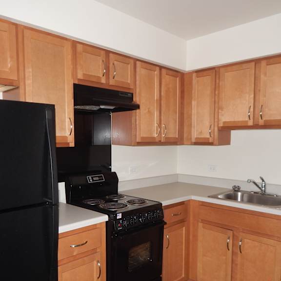 an empty kitchen with wooden cabinets and black appliances
