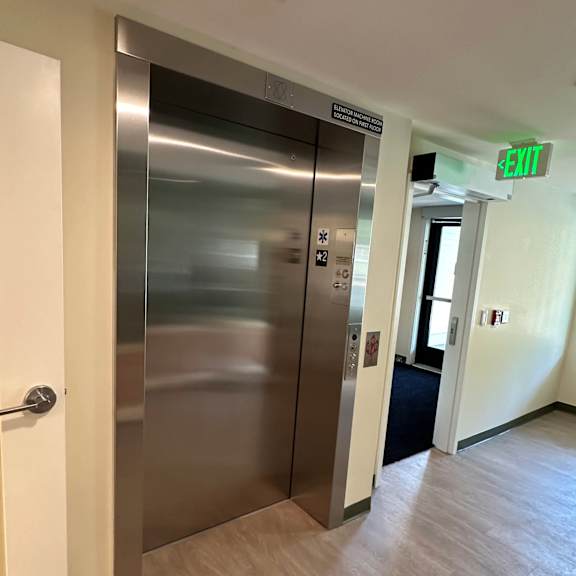 a stainless steel elevator in a hallway with a exit sign