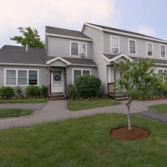 a grey house with a tree in front of it.