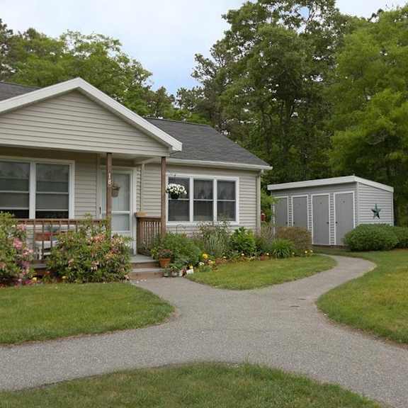 a house with a grey roof and a small shed in the backyard.