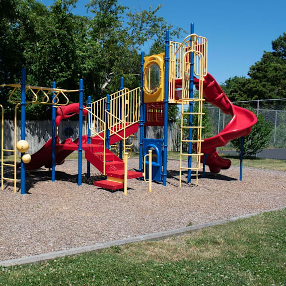 a playground with a red slide and yellow monkey bars