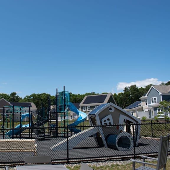 a playground with slides and other equipment in front of a row of houses