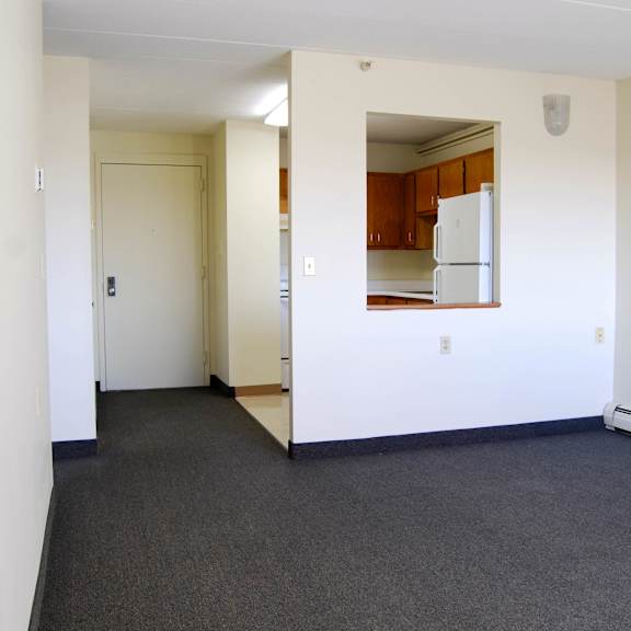 a white room with a kitchen in the background.