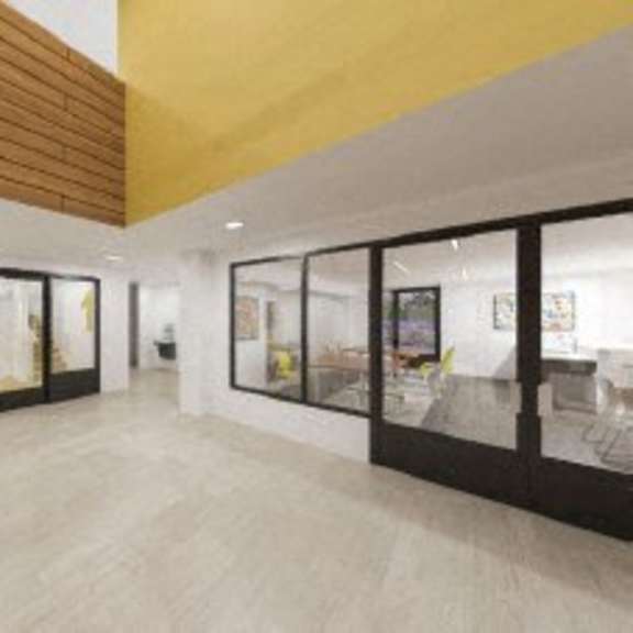 the lobby of a building with large windows and a yellow ceiling