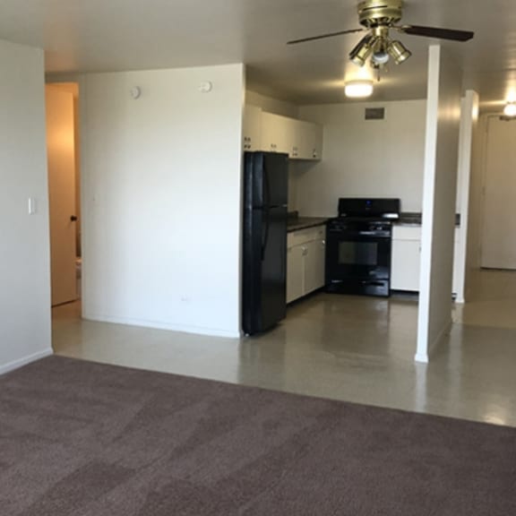 an empty living room and kitchen with a ceiling fan