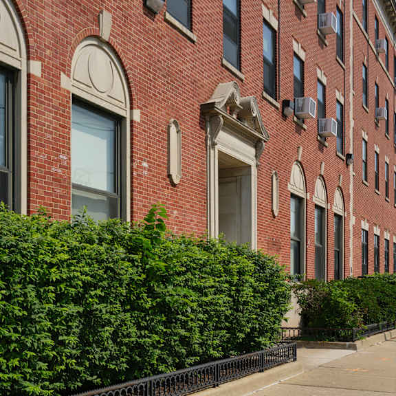 a red brick building with arched windows and a black fence.