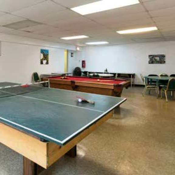 a ping pong table is in the middle of a room with a white wall and a door.