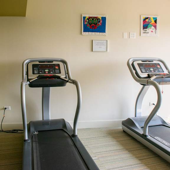 a room with two treadmills and two paintings on the wall