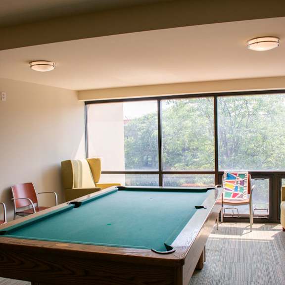 a pool table sits in the middle of a room with a large window