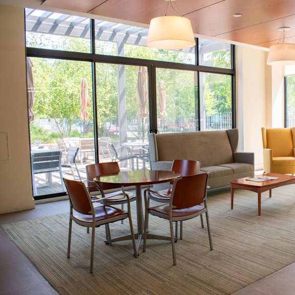 a room with a couch table and chairs and large windows