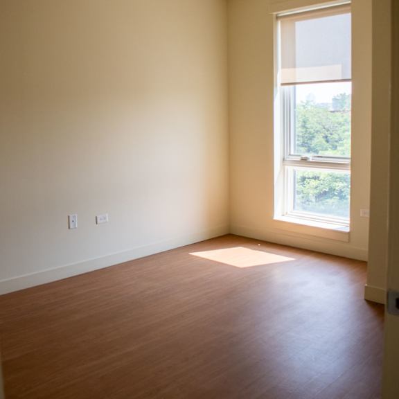 an empty room with a window and wooden floors
