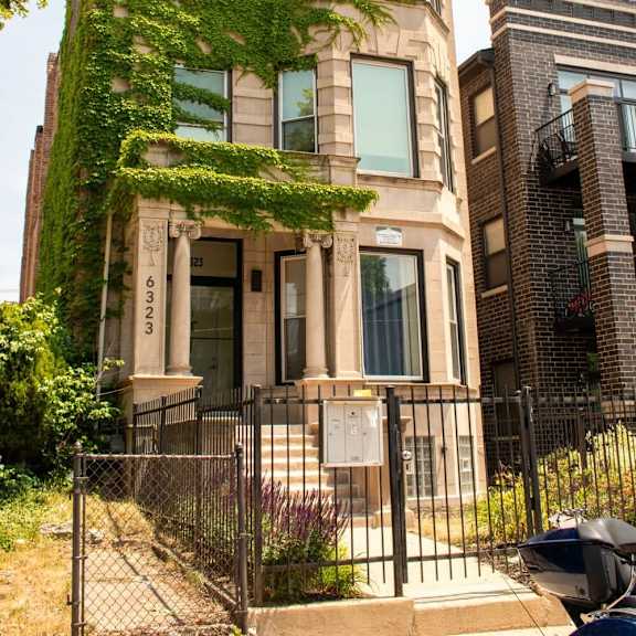 a condo building with a vine covered facade and a fence