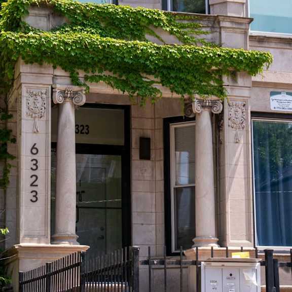 the facade of a building with columns and ivy on it