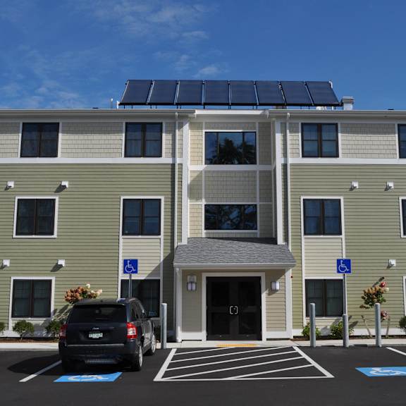 a building with solar panels on the roof and a car parked in a parking lot
