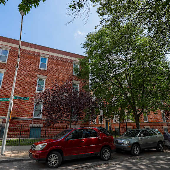 a red car is parked in front of a brick building.