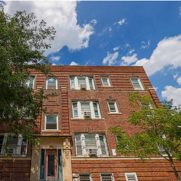 a red brick building with a blue sky and clouds in the background.