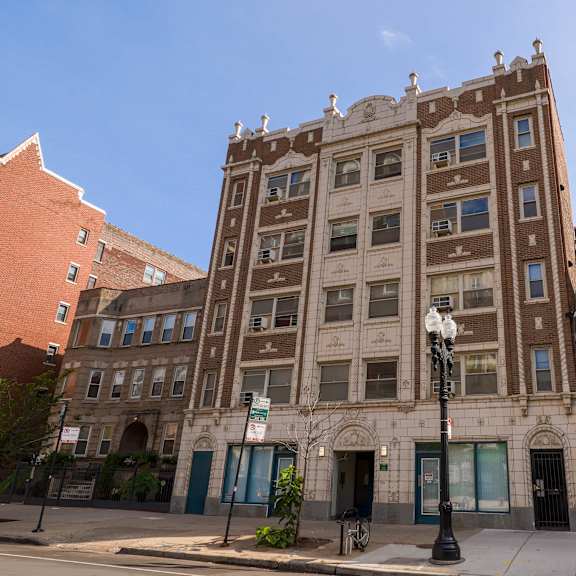a tall building with many windows is in the middle of a city street.