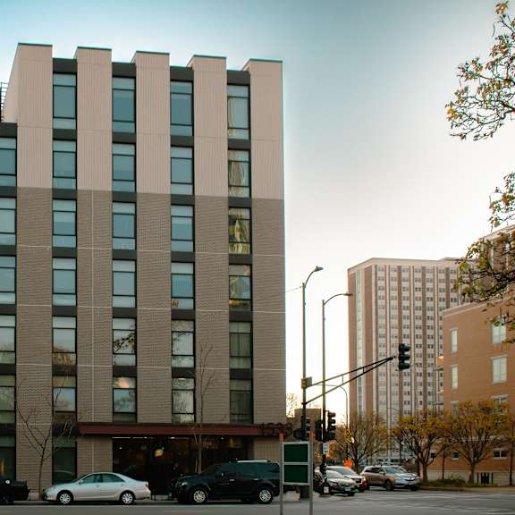 a large building with a lot of windows is in the middle of a street with cars parked in front.