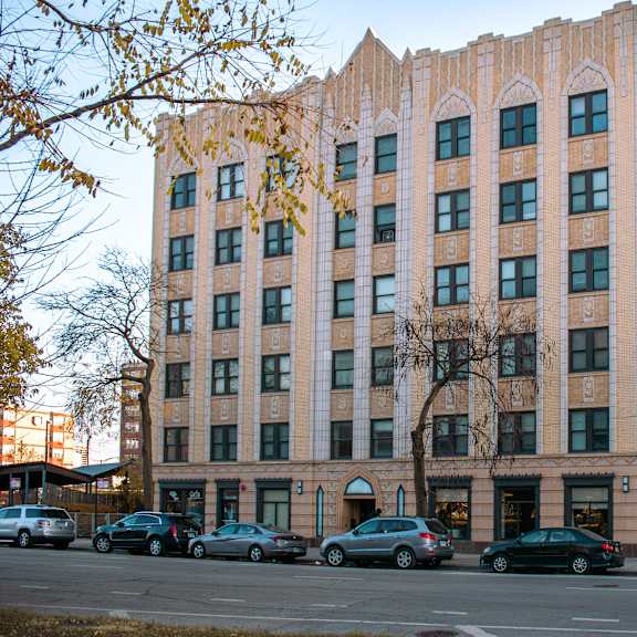 a large building with a lot of windows and cars parked in front.