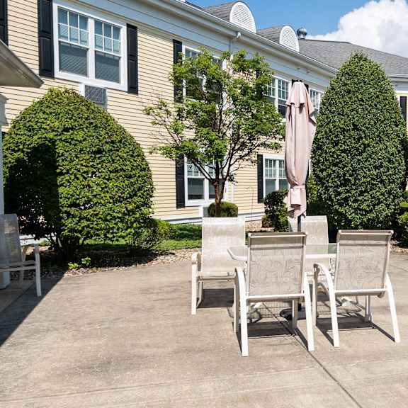 two chairs are placed on a patio in front of a house.