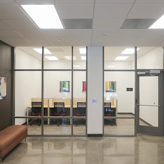 a conference room with a long table and chairs, a bench, and a door with an exit sign above it.
