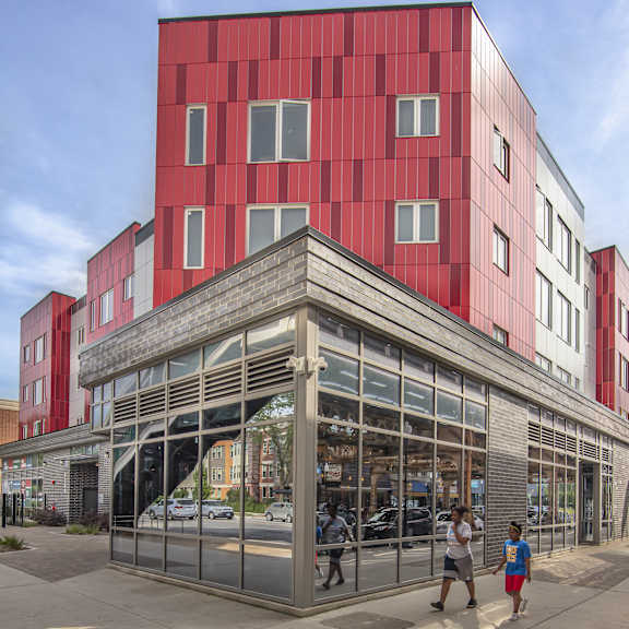 a red building with a large glass front and people walking in front.