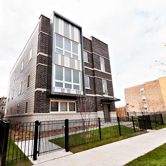 a modern house with a black fence in front.