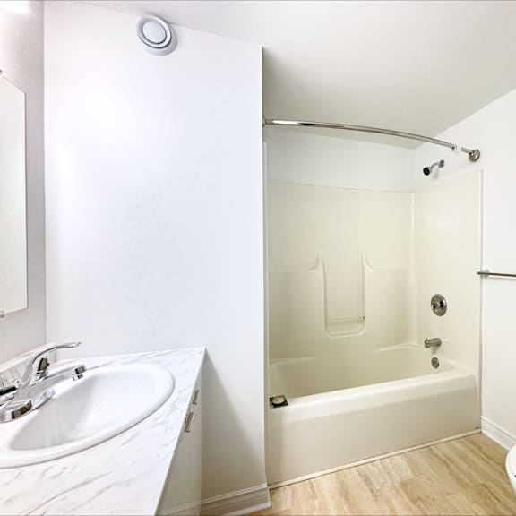 a white bathroom with a sink, toilet, and bathtub.
