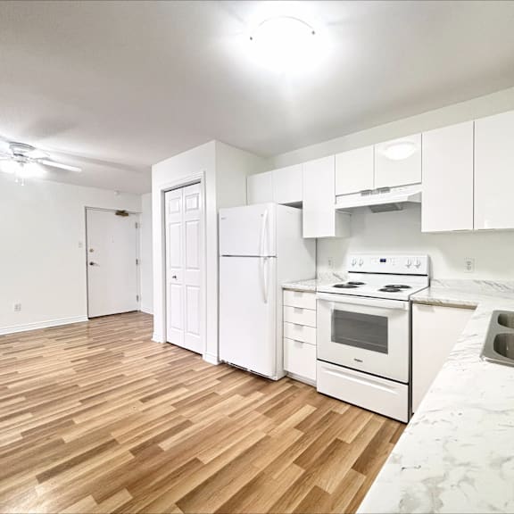 a kitchen with white appliances and wooden floors.