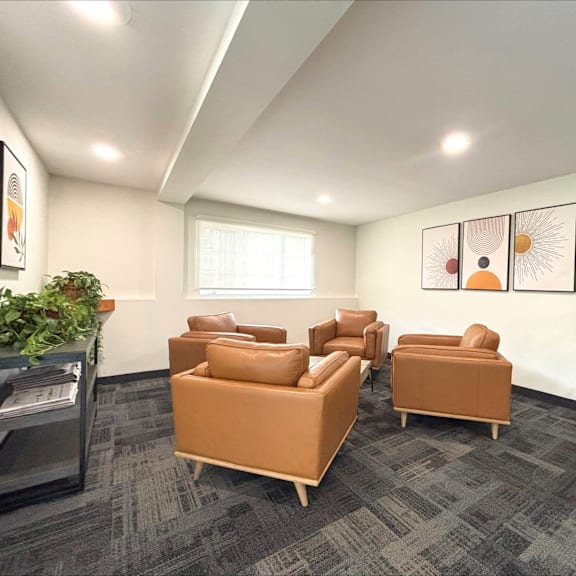 a room with grey carpet and brown chairs.