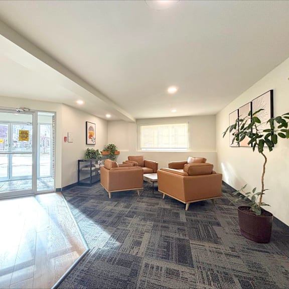 a spacious waiting room with a grey carpet and orange chairs.