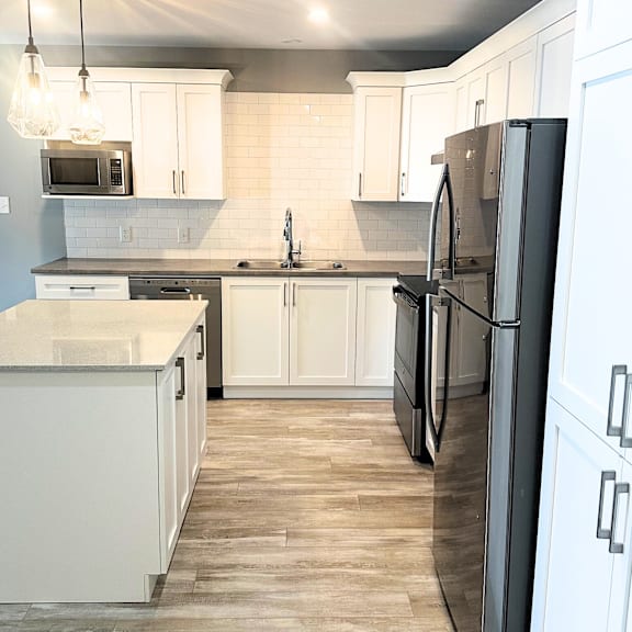 a kitchen with a black refrigerator and white cabinets.