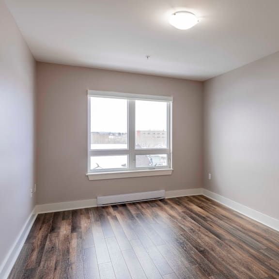 a room with a large window and wooden flooring.