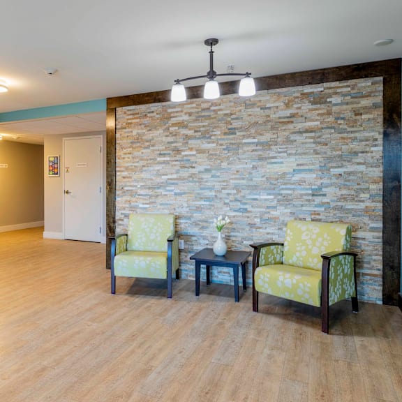two chairs and a table are in a room with a stone wall.