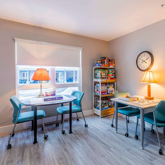 a room with a desk, chairs, and a clock on the wall.