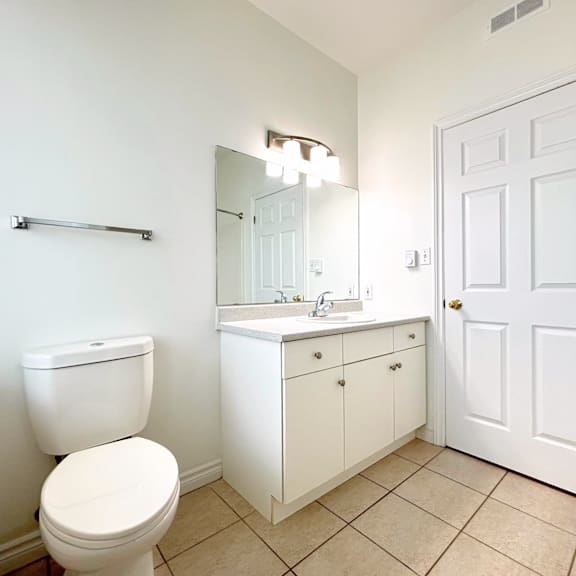 a white bathroom with a toilet, sink, and mirror.