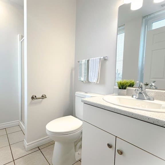 a white bathroom with a toilet, sink, and mirror.