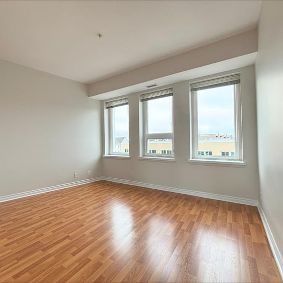 a room with wooden floors and three windows.