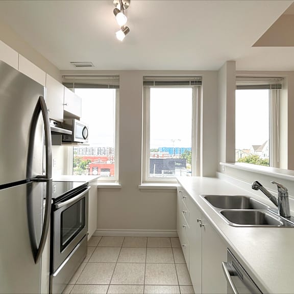 a kitchen with a stainless steel refrigerator and a window overlooking a cityscape.