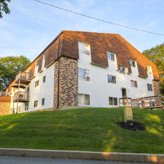 a white house with a brown roof and a stone chimney.