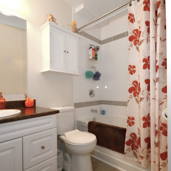 a white toilet sits in a bathroom with a brown towel on the tub.