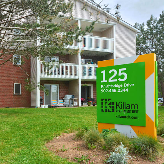 a sign for killam apartment rent in front of a building.