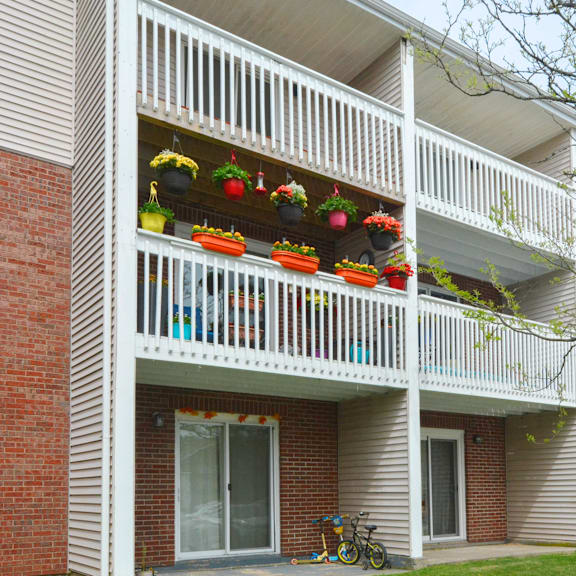 a balcony with white railings and several potted plants.