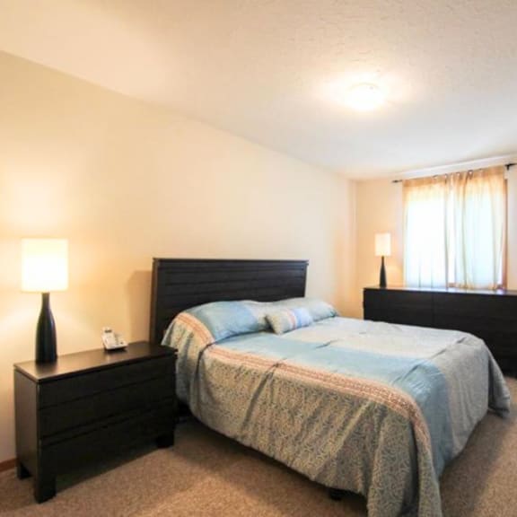 a bedroom with a bed, nightstand, and lamp.