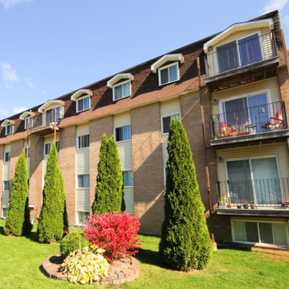 a row of apartment buildings with balconies and trees in front.