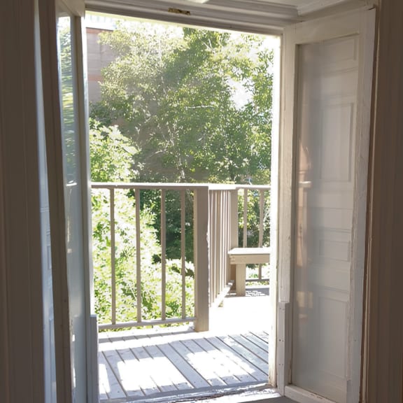 a white door opens to a balcony with a table and chairs.