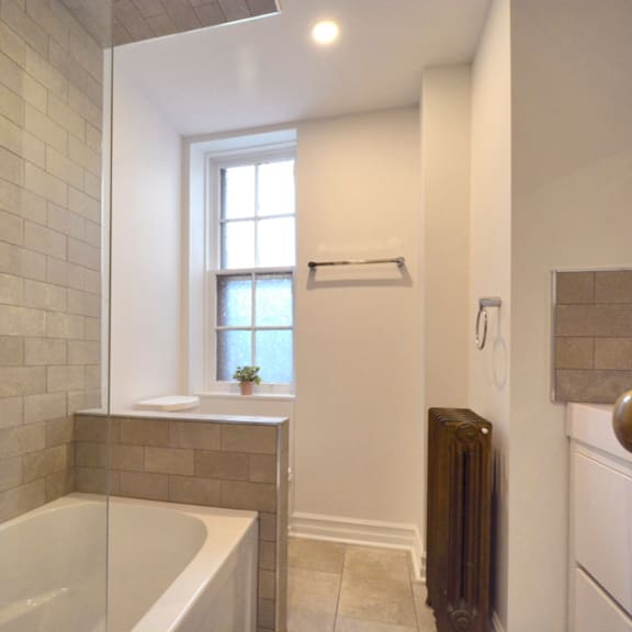 a bathroom with a tub, window, and radiator.
